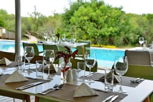 a table with wine glasses and napkins and a pool at Kruger Safari Lodge in Manyeleti Game Reserve