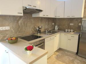 a kitchen with white cabinets and a sink and a stove at Apartment Domagoj in Bol