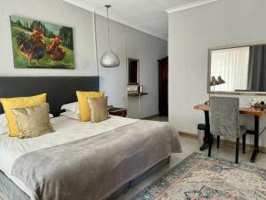 Un dormitorio con una cama, una mesa y un escritorio. en Rabbit Hole Hotel, en Krugersdorp