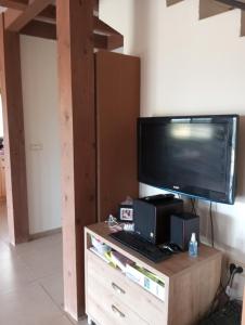 a television on top of a wooden stand with a keyboard at Lakeview Chalet in the Galilee - Master Bedroom Sublet in Kafr Mandā