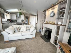 a living room with a white couch and a fireplace at Beautiful Caravan With Decking At Azure Seas Ref 32060az in Lowestoft