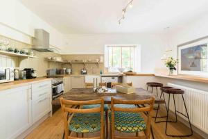 a large kitchen with a wooden table and chairs at Classic Cotswolds Apartment, The Little Coach House in Blockley