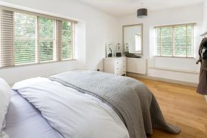 a white bedroom with a bed and a mirror at Classic Cotswolds Apartment, The Little Coach House in Blockley
