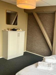 Schlafzimmer mit einem weißen Bett und einem Spiegel in der Unterkunft Bed and Breakfast De Zeehoeve in Harlingen