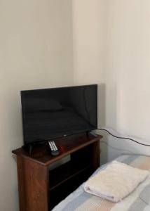 a flat screen tv sitting on a table next to a bed at Quartos Masculino - Romas House in Itu
