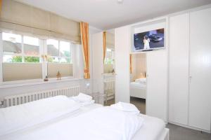 1 dormitorio con 2 camas blancas y 2 ventanas en Tunghörn Hüs, Whg 2, en Keitum