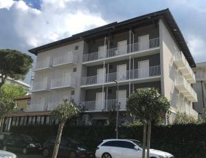 un grande edificio con auto parcheggiate di fronte di Hotel Villa Platani a Riccione