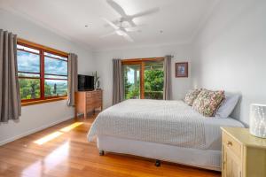 a white bedroom with a bed and a window at Cedia at Byron Bay Hinterland in Byron Bay