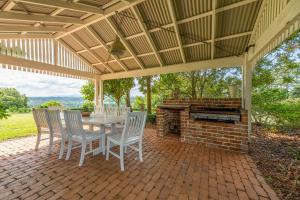 a patio with a table and chairs and a brick fireplace at Cedia at Byron Bay Hinterland in Byron Bay
