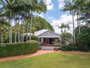 a house with palm trees in front of a yard at Cedia at Byron Bay Hinterland in Byron Bay
