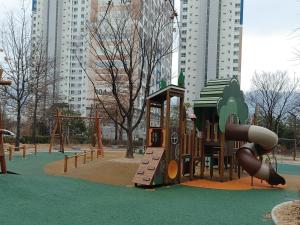 a playground with a slide in a park with tall buildings at Subhanallah guest house in Yangsan