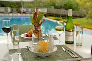 uma mesa com copos de vinho e um prato de comida em Kruger Safari Lodge em Reserva Manyeleti