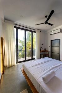 a bedroom with a large bed and a large window at El DESTINO Hiriketiya in Dickwella