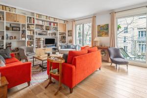salon z pomarańczowymi meblami i dużą półką na książki w obiekcie Spacious apartment with balcony in Paris - Welkeys w Paryżu