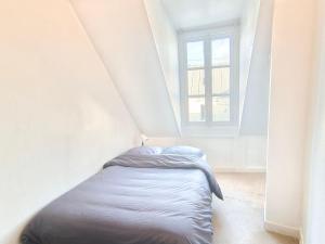 een bed in een witte kamer met een raam bij Appartement 4 personnes au centre Paris - Chatelet in Parijs