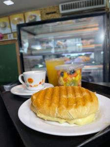 uma sandes num prato numa mesa com uma chávena de café em HOTEL GATAO em Sobral