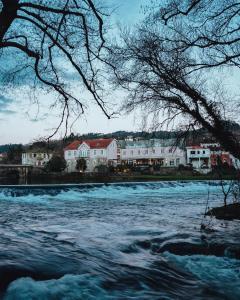 une vue sur une rivière avec des bâtiments en arrière-plan dans l'établissement Herança do Vez, à Arcos de Valdevez