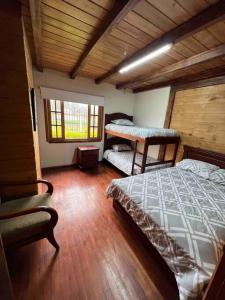 sypialnia z 2 łóżkami i oknem w pokoju w obiekcie Alegre villa con piscina para uso familiar de 3 dormitorios w mieście Paute