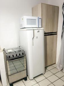 een magnetron bovenop een koelkast naast een fornuis bij Kitnet no Melhor Ponto de Bombinhas in Bombinhas