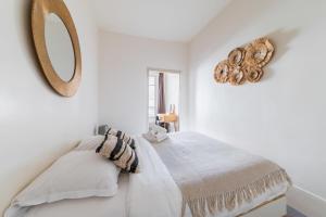- une chambre avec des murs blancs et un miroir mural dans l'établissement Appartement Paisible Proximité des Halle - 4P, à Paris