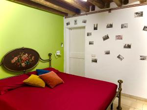 a bedroom with a bed with red sheets and pictures on the wall at Casetta Vigo in Chioggia
