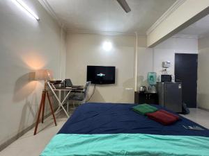 een slaapkamer met een bed, een bureau en een televisie bij Fully Furnished Studio Apartment in Pune