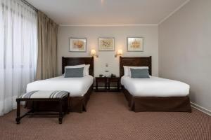 サンティアゴにあるTeclados Hotelのベッド2台と窓が備わるホテルルームです。