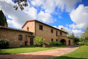 um grande edifício de tijolos com um pátio verde em Podere Fignano, holiday home - apartments, renovated 2024 em Montaione