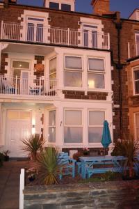 陶因的住宿－Beach Front Apartment in Tywyn，前面有两根蓝色长椅的房子