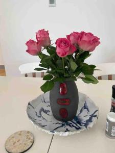 um vaso cheio de rosas rosas sentadas num prato em Hendrix’s cottage em Lincoln