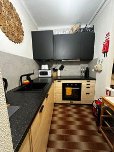 eine Küche mit einer schwarzen Arbeitsplatte und Holzschränken in der Unterkunft Suf's Bonfim View in Setúbal
