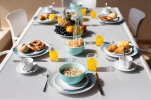 - une longue table avec des assiettes de produits pour le petit-déjeuner et du jus d'orange dans l'établissement Balcon los Gigantes Beautiful, à Puerto de Santiago