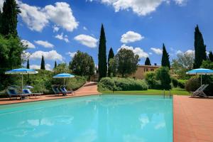 a swimming pool with two chairs and umbrellas at Podere Fignano, holiday home - apartments, renovated 2024 in Montaione