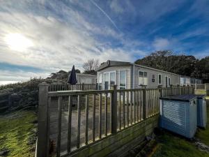 a house with a fence and an umbrella at 6 Berth Luxury Caravan With Full Sea Views At Azure Seas In Suffolk Ref 32069az in Lowestoft