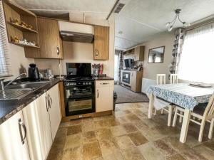 a kitchen with a stove and a table in it at 6 Berth Luxury Caravan With Full Sea Views At Azure Seas In Suffolk Ref 32069az in Lowestoft