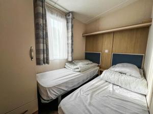 two beds in a small room with a window at 6 Berth Luxury Caravan With Full Sea Views At Azure Seas In Suffolk Ref 32069az in Lowestoft