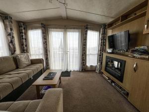 a living room with a couch and a tv at 6 Berth Luxury Caravan With Full Sea Views At Azure Seas In Suffolk Ref 32069az in Lowestoft