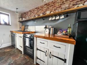 a kitchen with white cabinets and a brick wall at Beautiful 04 Berth Cottage With A Private Hot Tub In Norfolk Ref 99002hc in Pentney
