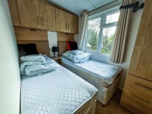 a bedroom with two twin beds and a window at Pet Friendly, Luxury Caravan For Hire In Suffolk By The Beach Ref 32203og in Lowestoft