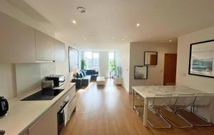 een keuken en een woonkamer met een tafel en een bank bij Bracknell Stylish Two Bedroom Apartment in Bracknell