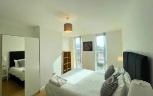 a white bedroom with a bed and a mirror at Bracknell Stylish Two Bedroom Apartment in Bracknell