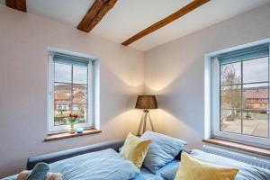 a bedroom with two windows and a couch with pillows at Ferienwohnung Haseltal in Rotenburg an der Fulda