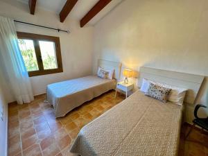 een slaapkamer met 2 bedden en een raam bij Finca Es Trenc mit Pool I Whirlpool I BBQ I Klima in Campos