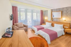 una camera d'albergo con due letti e un tavolo di Solo Grand Boshuri Hotel Wellness Resort a Gori