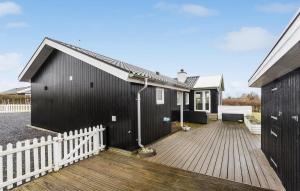 a black house with a white fence and a wooden deck at Lovely Home In Bogense With Wifi in Bogense