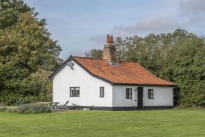 Great Ellingham的住宿－Pettingalls Farm Cottage，一座白色的房子,在田野上有一个红色的屋顶