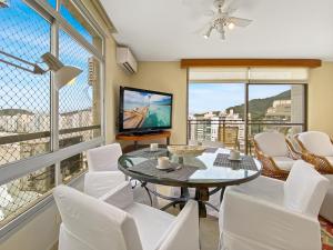 un salon avec une table, des chaises et une télévision dans l'établissement Vista incrível Beira-Mar Espaçoso 4 Qts AC, à Guarujá