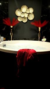 een badkamer met een wit bad met twee rode veren bij O' Plaisirs Interdits - Loveroom in Caen