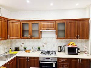 uma cozinha com armários de madeira e um micro-ondas em Просторная 3 комнатная квартира em Taraz