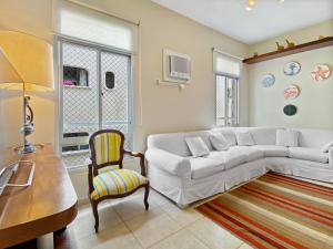 - un salon avec un canapé blanc et une chaise dans l'établissement Vista incrível Beira-Mar Espaçoso 4 Qts AC, à Guarujá